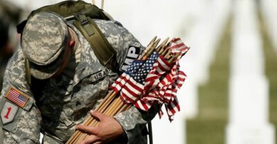 soldier placing flags at cemetery